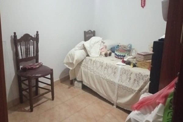 Cozy bedroom with a bed, chair, and personal belongings in Hinojares, Jaen village property.