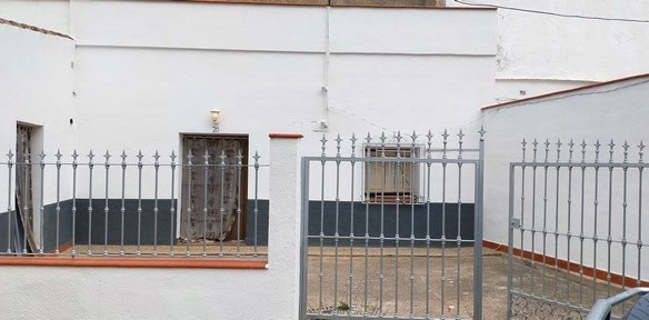 Cave house exterior in Benamaurel, Granada with metal gate and white walls.