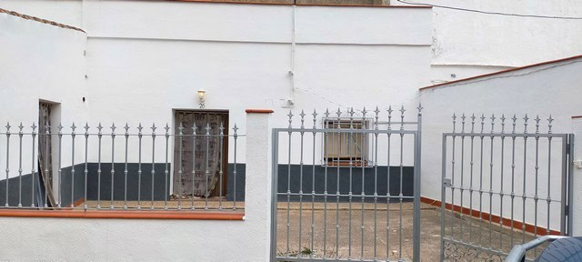 Cave house exterior in Benamaurel, Granada with metal gate and white walls.