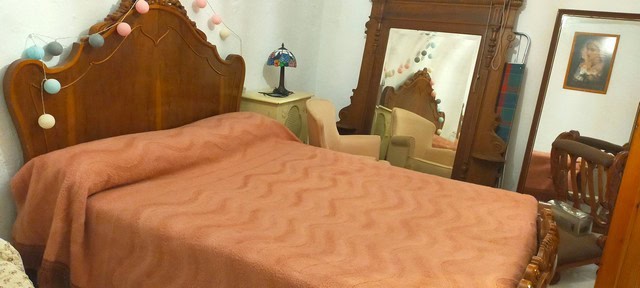 Cozy bedroom with vintage wooden furniture and warm lighting in a cave house in Benamaurel, Granada.