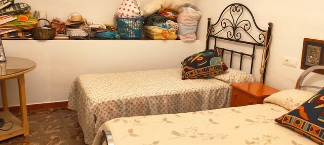 Traditional cave house interior in Benamaurel, Granada, with cozy beds and storage shelves.