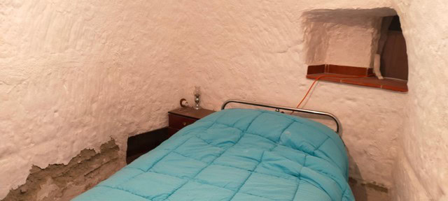 Charming village bedroom with rustic stone walls and cozy atmosphere in Benamaurel, Granada.