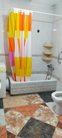 Bright bathroom with colorful shower curtain in a traditional village home.