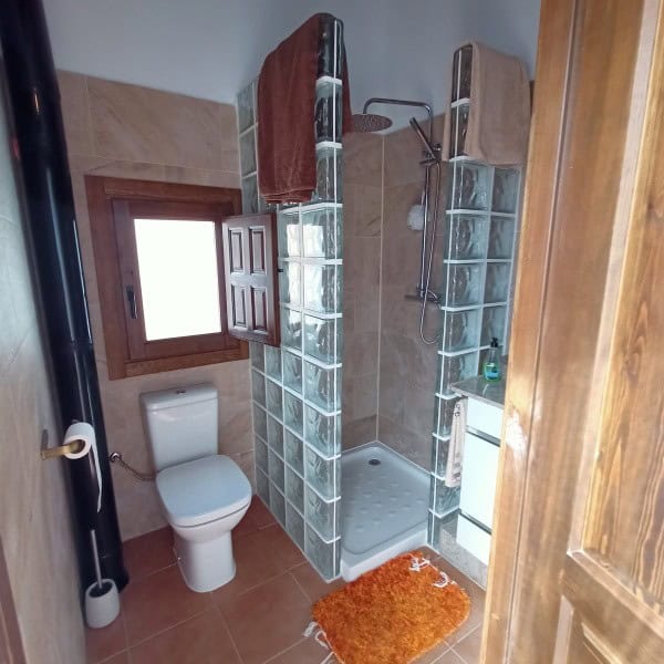 Compact bathroom with shower, toilet, and window in a village property.