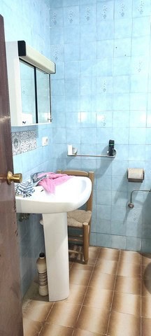Charming bathroom in Tijola town house, featuring blue tiled walls, a sink, mirror, and basic fixtur.