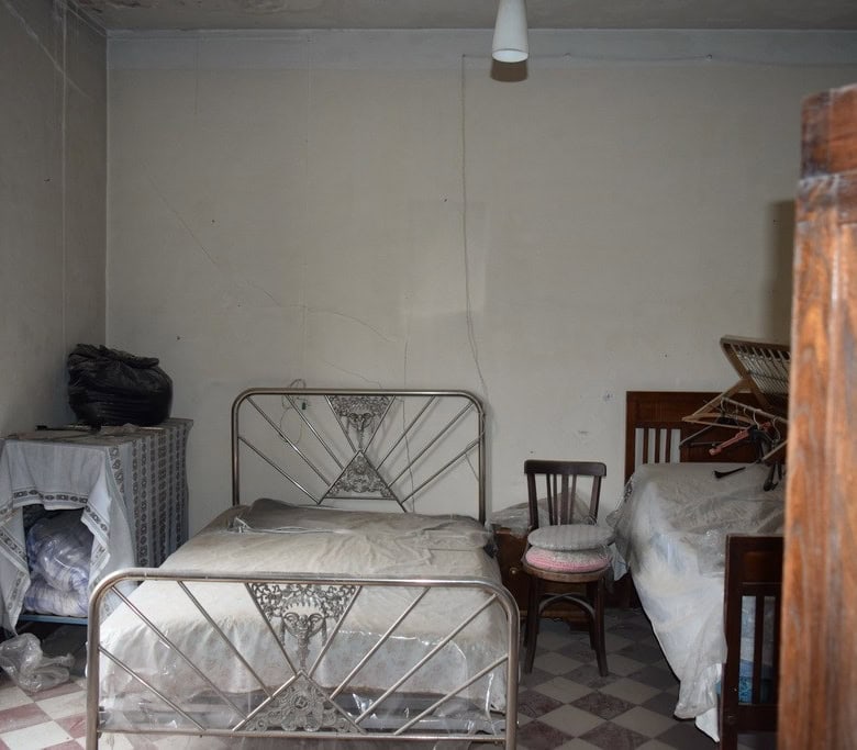 Interior of a modest town house bedroom in Baza, Granada with metal beds and simple furnishings.
