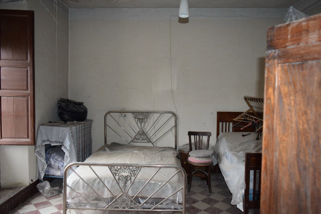 Interior of a modest town house bedroom in Baza, Granada with metal beds and simple furnishings.