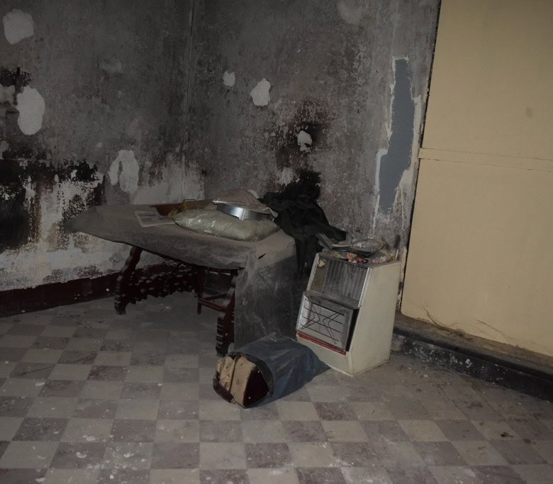Old kitchen with damaged walls and worn flooring in a town house in Baza, Granada.
