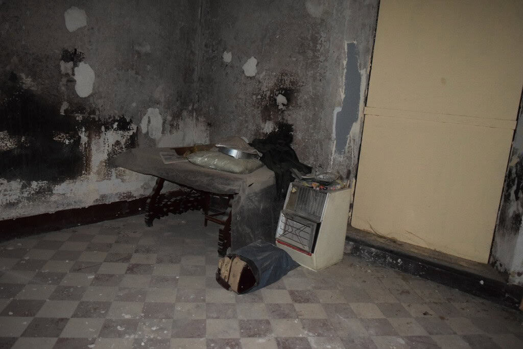 Old kitchen with damaged walls and worn flooring in a town house in Baza, Granada.