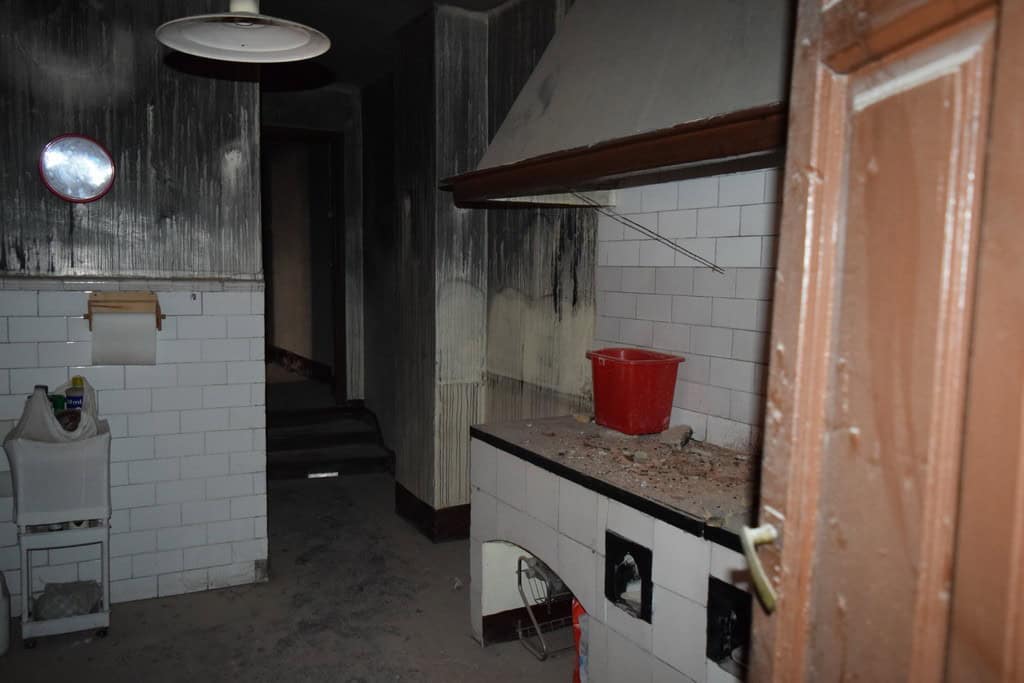 Interior of a town house kitchen in Baza, Granada, showing damaged walls and outdated appliances.