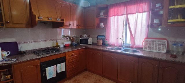 Interior view of a traditional kitchen in Cortes de Baza, Granada, with wooden cabinets and pink cur.