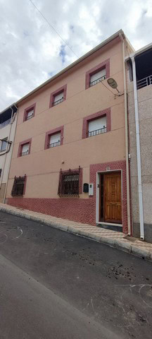 Town house in Tijola, Almeria with a wooden front door and small windows, situated on a quiet street.