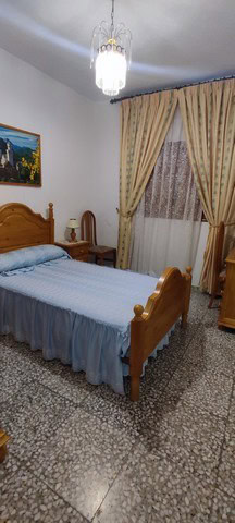 Charming town house bedroom in Tijola, Almeria with classic wooden furniture and elegant curtains.