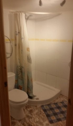 Small bathroom with shower, toilet, and curtain in Seron, Almeria.