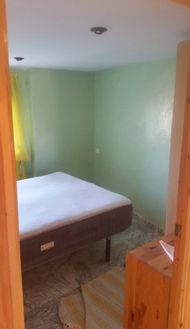 Interior view of a simple bedroom in Seron, Almeria, featuring a bed, green walls, and natural light.