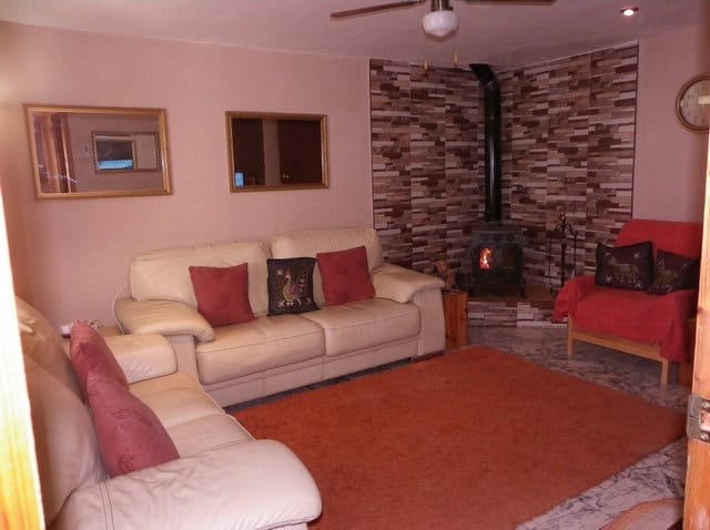 Spacious living room featuring a fireplace, comfortable sofas, and warm decor in a village property.