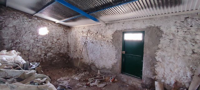 Interior view of a rustic town house in Tijola, Almeria, showing unfinished walls and a simple door.