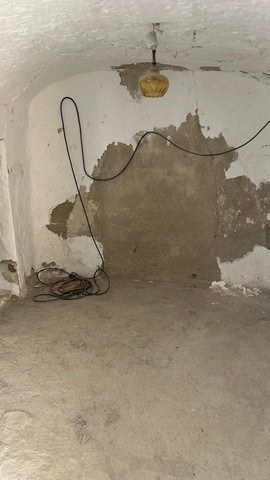 Interior of a rustic cave house with unfinished walls and exposed wiring in Cantarranas, Granada.