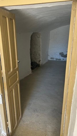 Interior view of a cave house in Cantarranas, Granada, showing rustic stone walls and simple floorin.