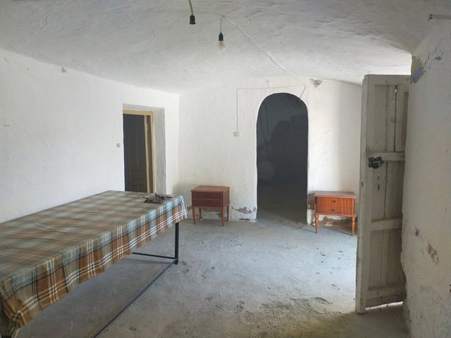 Interior view of a traditional cave house in Cantarranas, Granada, showcasing rustic white walls and.