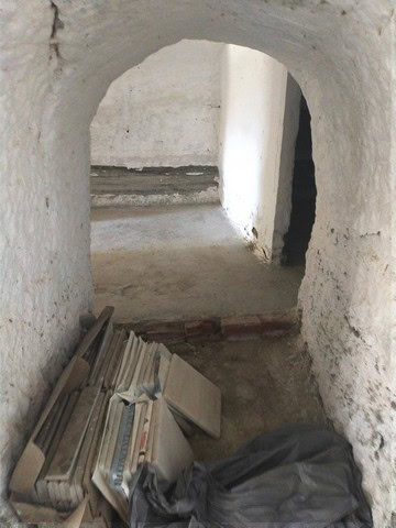 Cave house interior with arched doorway and construction materials in Cantarranas, Granada.