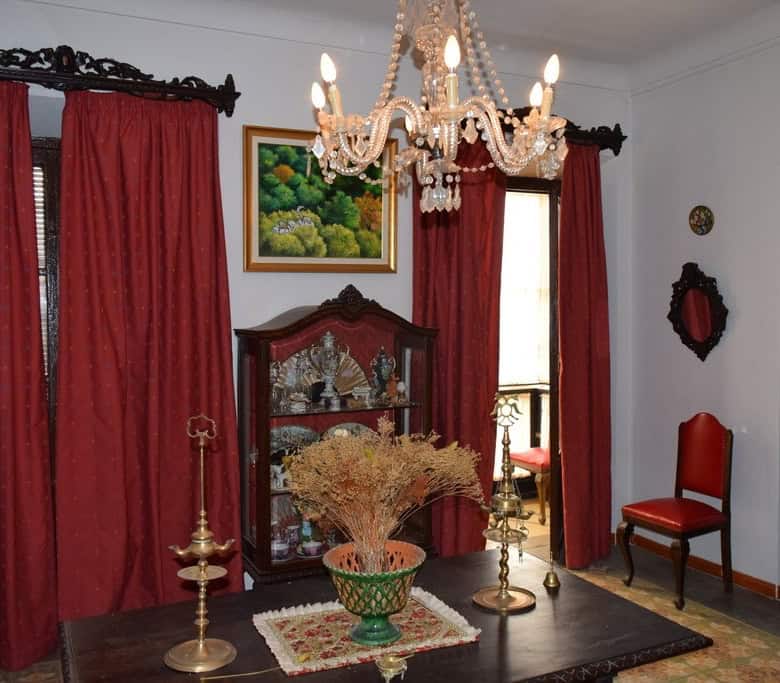 Cozy living room with vintage furniture, elegant chandelier, and vibrant red curtains in Baza, Grana.