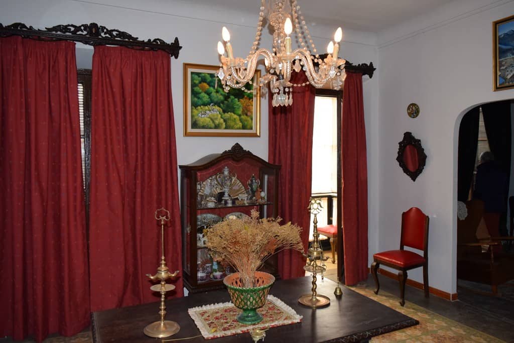 Cozy living room with vintage furniture, elegant chandelier, and vibrant red curtains in Baza, Grana.