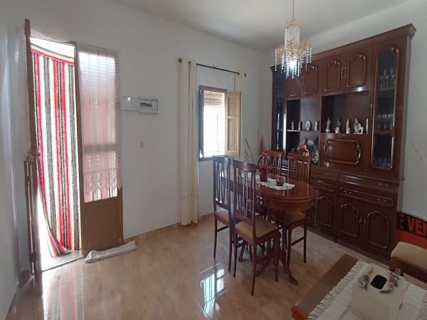Village property interior with dining table and wooden cabinet in Villanueva de las To, Granada.