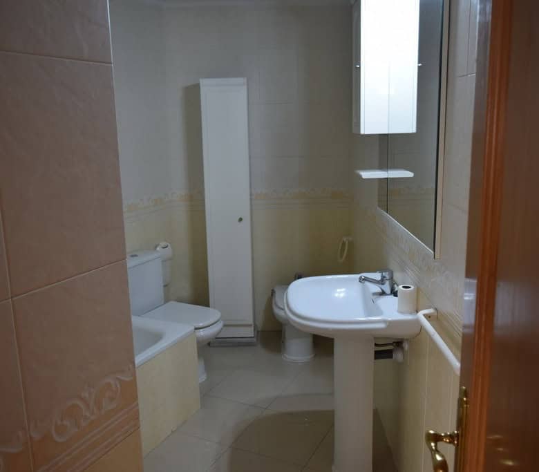 Bathroom in an apartment located in Baza, Granada, featuring a toilet, sink, and mirror.