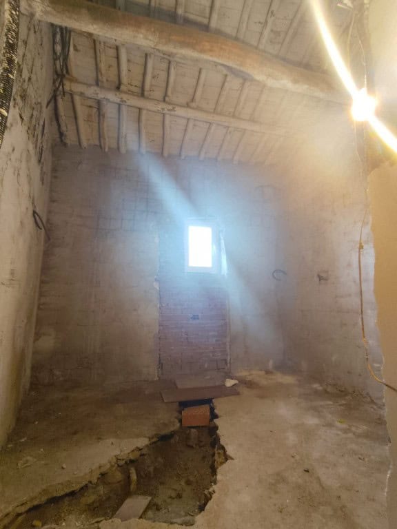 Interior of a rustic cave house with sunlight streaming through a small window.