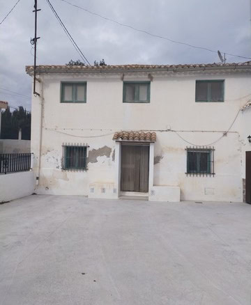 Traditional village house in Los Olivos, Granada, with white exterior walls and a rustic wooden door.