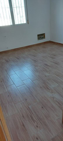 Bright empty room with wooden flooring and a large window.