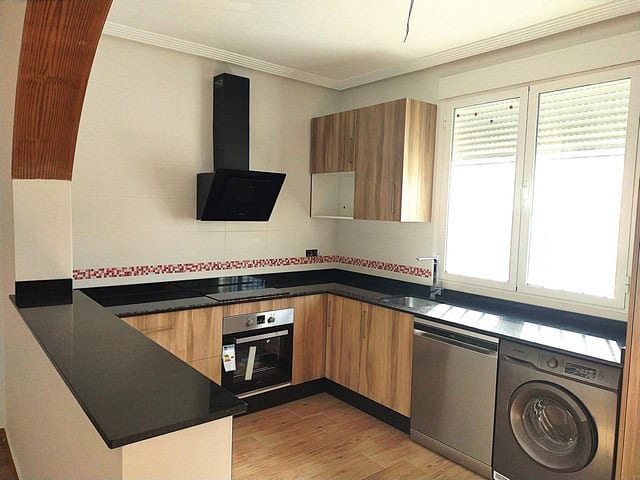 Kitchen with wooden cabinets, black countertops, and modern appliances in Cantoria villa.