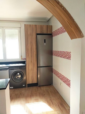 Spacious kitchen featuring a stainless steel refrigerator and washing machine in a bright, modern Ca.