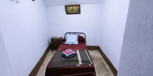 Cozy bedroom in a village property in Fontanar, Jaen with simple furnishings and white walls.