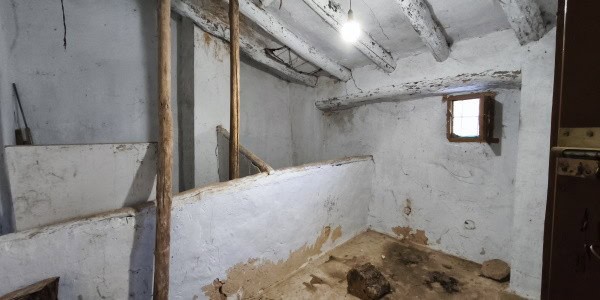 Interior view of a rustic village property in Fontanar, Jaen, showing exposed beams and aged walls.
