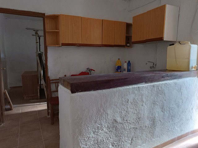 Charming rural property kitchen in Caniles, Granada with wooden cabinets and basic amenities. Perfec.