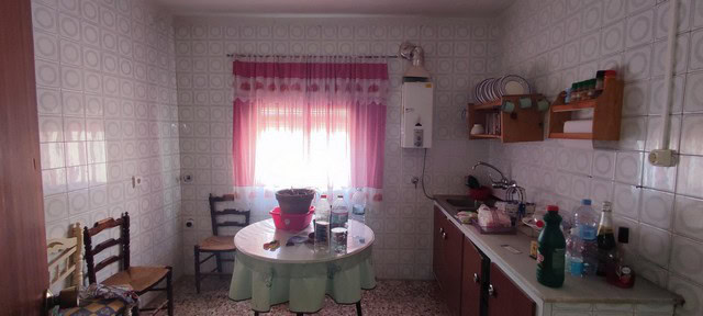 Village property interior with kitchen and dining area in Seron, Almeria. Cozy space with pink curta.