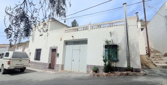 Cave house in Fontanar, Jaen with white exterior and small garden area.