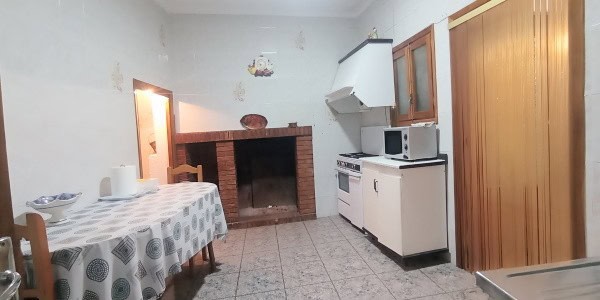 Interior view of a rustic cave house in Fontanar, Jaen, showcasing a cozy kitchen with a fireplace.