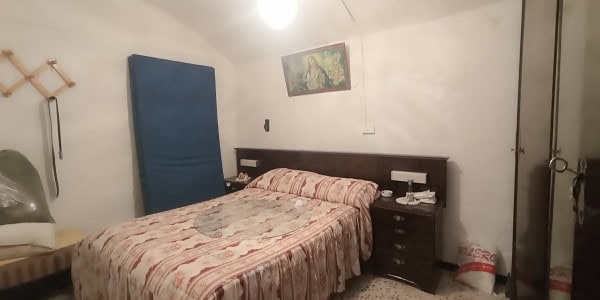 Charming cave house interior in Fontanar, Jaen, featuring a cozy bedroom with simple furnishings.