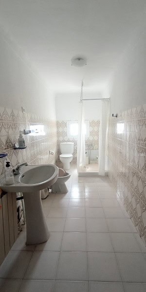 Bright bathroom in a cave house in Fontanar, Jaen with white fixtures and tiled walls.