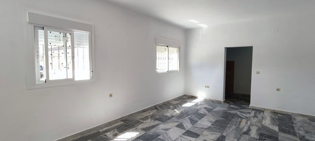 Spacious empty room in a rural property in Macael, Almeria, with white walls and marble flooring.