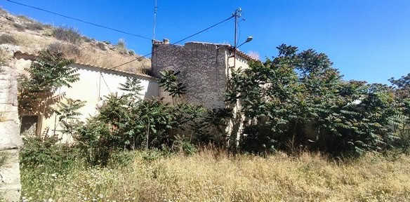 Cave house nestled in La Alqueria, Granada, surrounded by natural landscape and greenery.