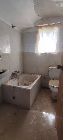 Old cave house bathroom with bathtub and toilet in La Alqueria, Granada. Rustic, unfinished interior.