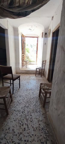 Cave house interior with rustic chairs and natural light from the entrance in La Alqueria, Granada.