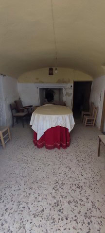 Interior of a traditional cave house with a round table and chairs in La Alqueria, Granada.