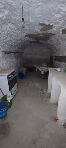 Interior of a rustic cave house with a low ceiling and exposed rock formations in La Alqueria, Grana.
