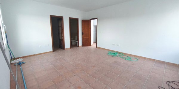 Spacious empty room in a village property in Fontanar, Jaen, with tiled floors and white walls.
