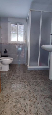 Cozy bathroom with shower, toilet, and window in a village property in Somontin, Almeria.